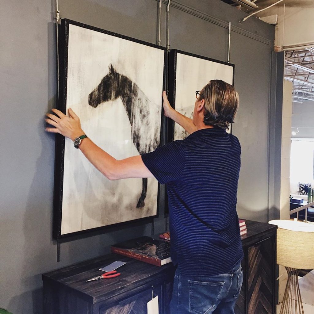 Intaglia Design Consultant, Bobby Krechnyak, hanging art in the store.